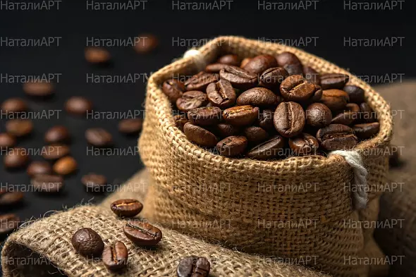 Свежие кофейные зёрна в мешке из мешковины на стильном тёмном фоне